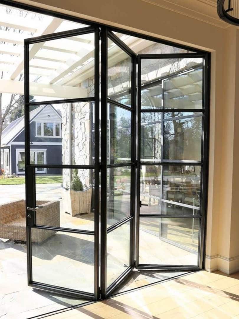 Black‑framed aluminium bifold doors fully opened onto a patio, showing modern slimline aluminium design.