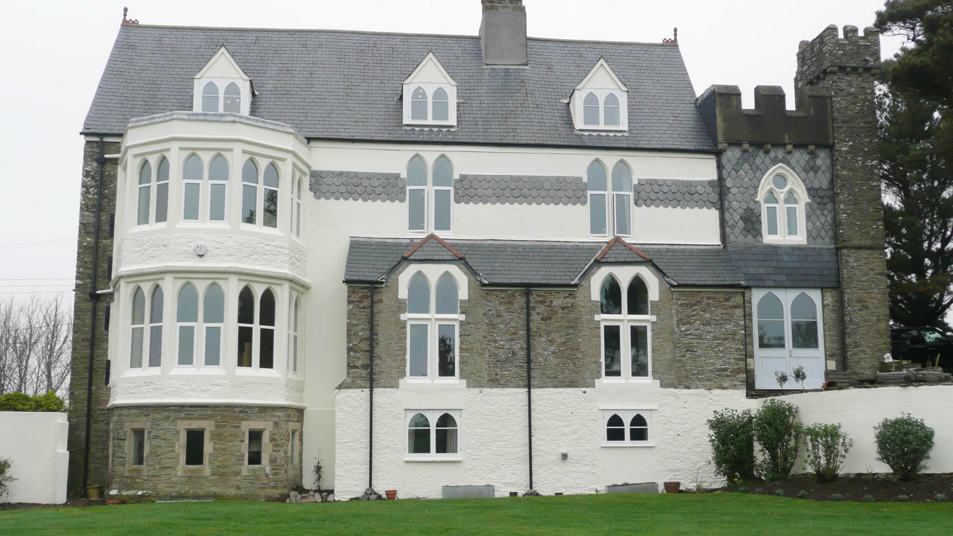 Heritage aluminium windows installed in a period stone property, featuring tall arched and curved window designs.