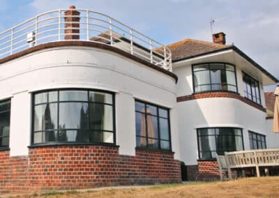 Curved heritage aluminium windows with slim black frames on an Art Deco‑style house.