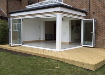 Heritage aluminium bi‑fold doors fully opened on a modern home extension with a flat roof.