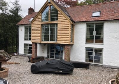 Large heritage aluminium gable window with slim black frames on a modern two‑storey house.