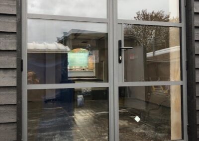 Heritage aluminium glass door with a grey frame set into dark timber cladding.