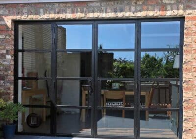 Heritage aluminium multi‑pane glass door with a black frame set into a brick wall.