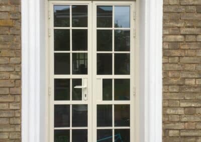 Heritage aluminium multi‑pane door with a cream frame set into a brick wall.