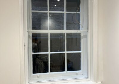 Heritage aluminium multi‑pane window with a white frame above a radiator cover in a modern interior.