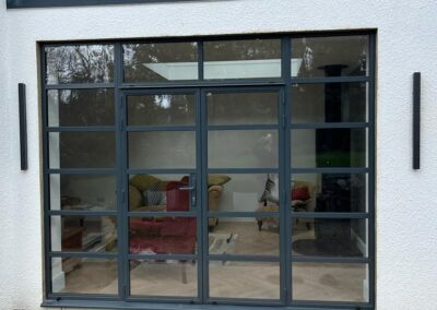 Heritage aluminium sliding door with a dark frame set into a white rendered exterior wall.