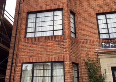 Heritage aluminium windows with slim black frames on a multi‑storey red‑brick building.