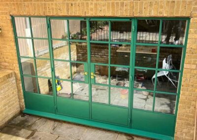 Green aluminium framed glass doors on a brick extension with modern glazing.