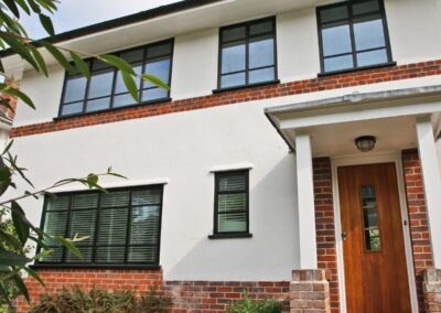 Modern home exterior featuring black aluminium windows and a wooden front door.