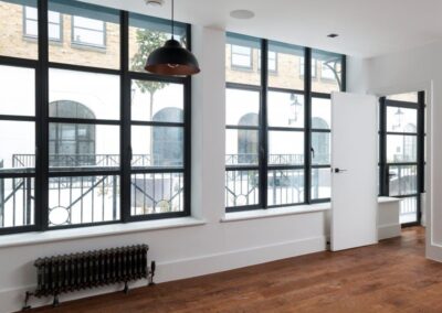 Contemporary room with black aluminium windows, wooden flooring and white interior walls.