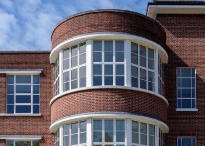 Curved brick bay window with white frames on a period property exterior.